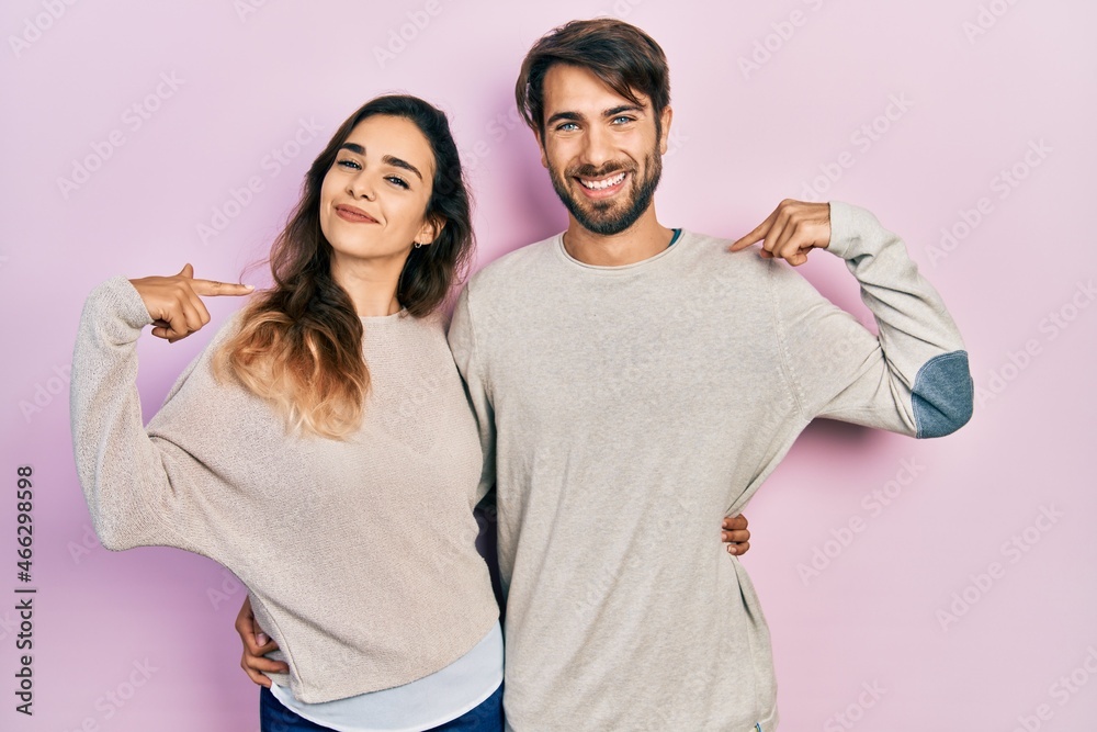 Obraz premium Young hispanic couple wearing casual clothes looking confident with smile on face, pointing oneself with fingers proud and happy.