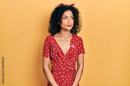 Young latin girl wearing summer dress smiling looking to the side and staring away thinking.