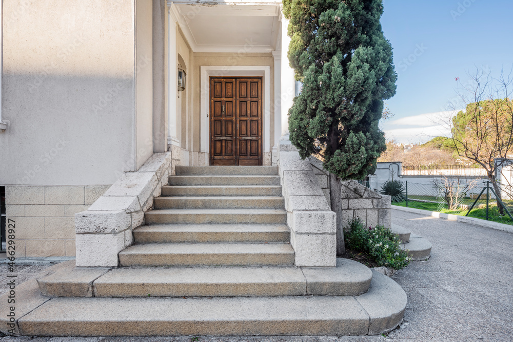 Fototapeta premium Granite stone stairs that give access to a wooden door with an entrance panel to a private home