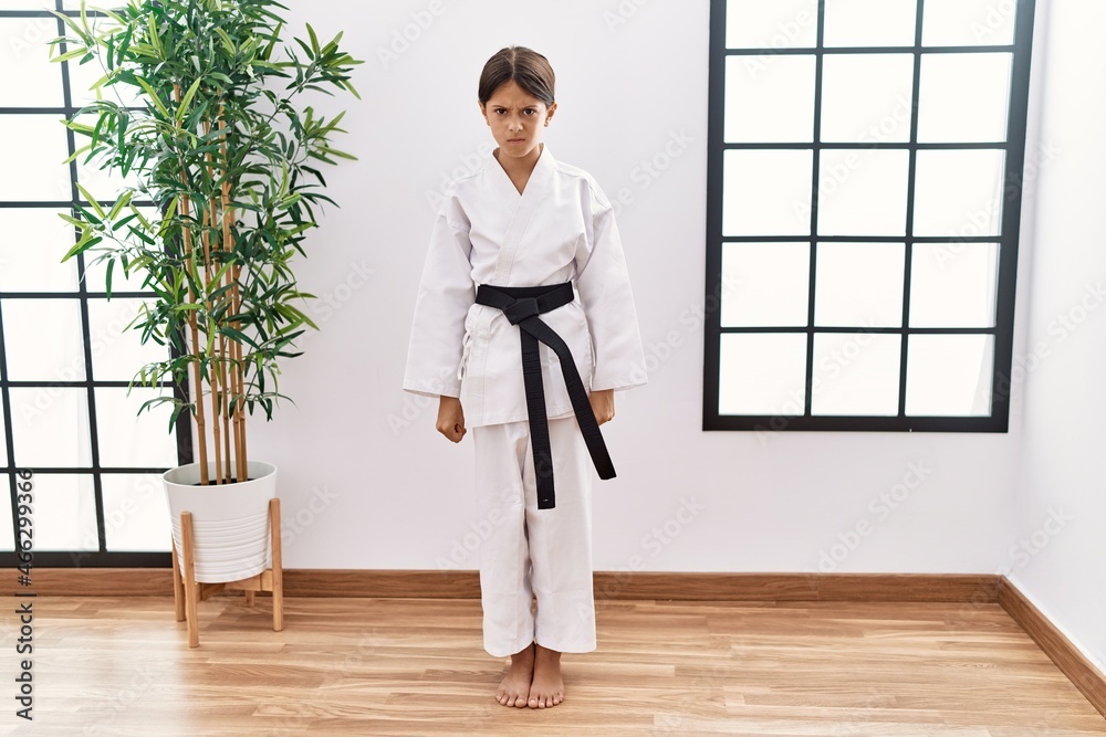 Young hispanic girl wearing karate kimono and black belt skeptic and nervous, frowning upset because of problem. negative person. Young hispanic girl wearing karate kimono and black belt skeptic and nervous, frowning upset because of problem. negative person.