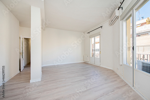 Newly painted empty room with wooden floors  floor-to-ceiling viewpoints and air conditioning unit