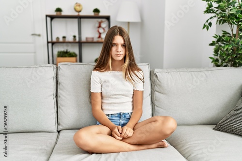 Young brunette teenager sitting on the sofa at home skeptic and nervous, frowning upset because of problem. negative person.