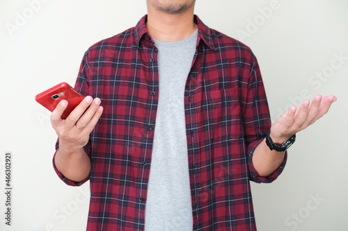 A guy holding mobile phone while showing confused gesture photo