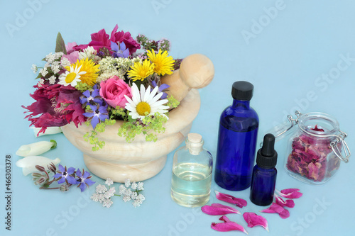 Healing herbs and flowers for alternative herbal plant medicine remedies  with aromatherapy essential oil bottles. Nature health and wellness concept. On mottled blue.
