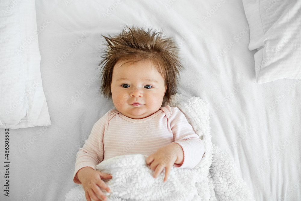 The baby is 3 months old. A beautiful newborn baby girl lies on a white sheet. The baby is 3 months old. A beautiful newborn baby girl lies on a white sheet.