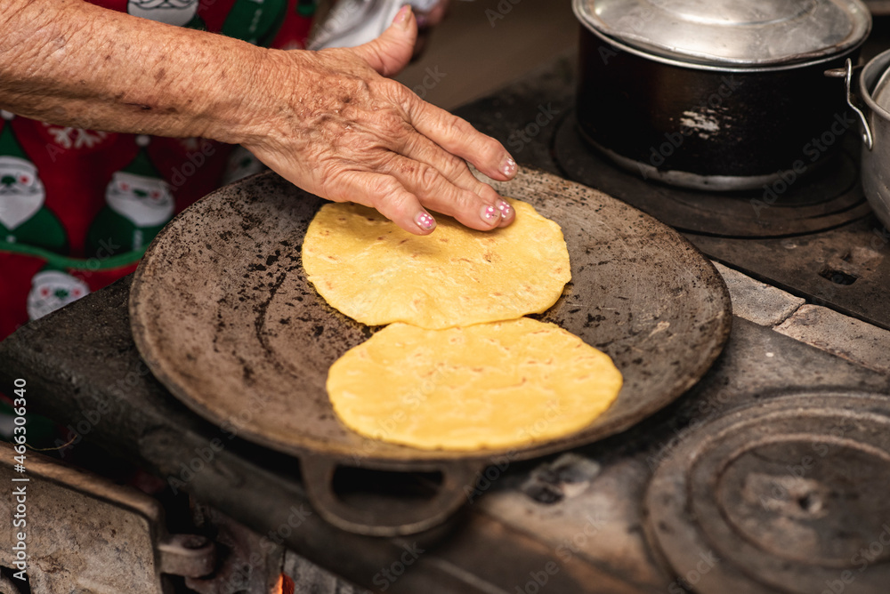 Mano de una mujer adulta mayor cocinando tortillas caseras de costa