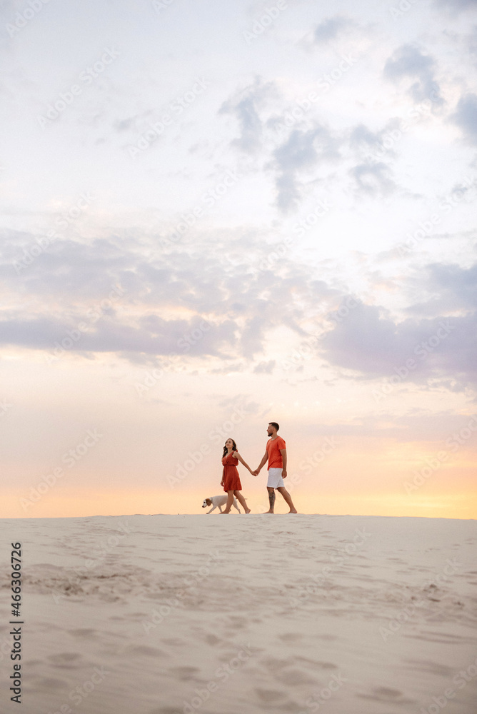 Fototapeta premium young couple in orange clothes with dog