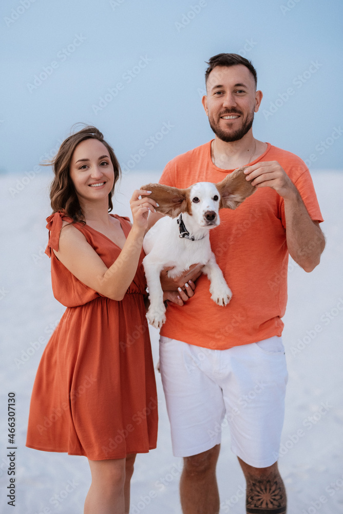 young couple in orange clothes with dog young couple in orange clothes with dog