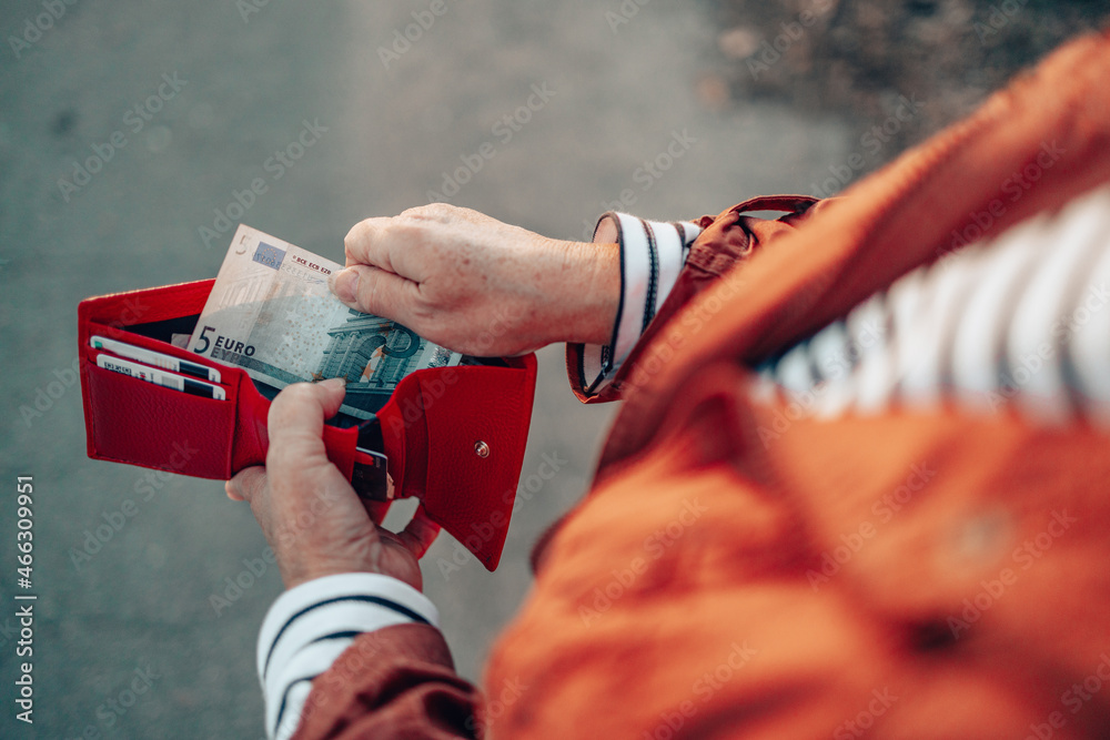Female takes out 5 euro banknote from a red leather wallet on the street - obrazy, fototapety, plakaty 