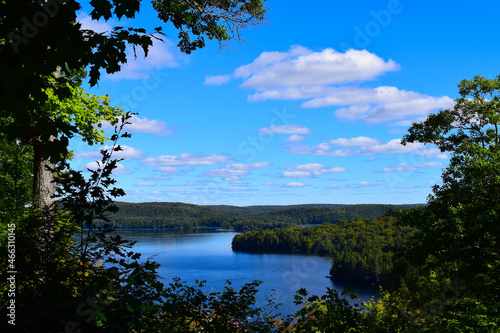 Lake with cloudy sky, surrounded by lush green foliage, in Algonquin Park, Canada © LE-gals Photography