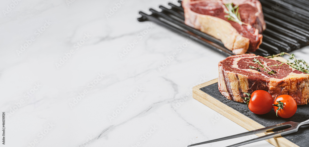 three delicious steaks ready to grill on a white marble surface