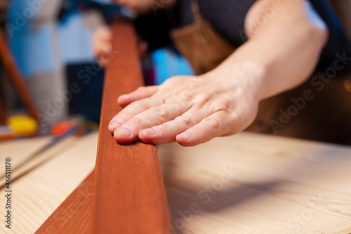 A carpenter checking smoothness of wood material. Woodworker preparing planks for work