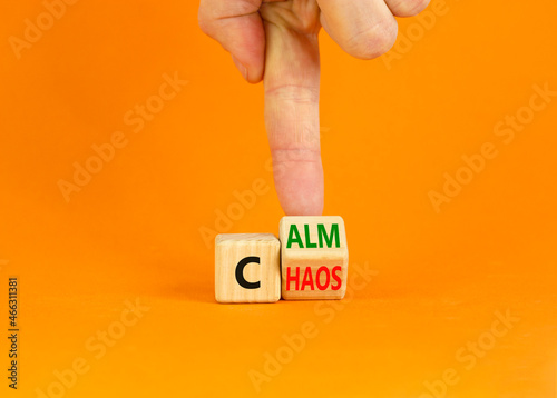 Stop chaos, time to calm. Businessman turns a wooden cube and changes the word 'chaos' to 'calm'. Beautiful orange background, copy space. Business, psuchological and chaos or calm concept. photo