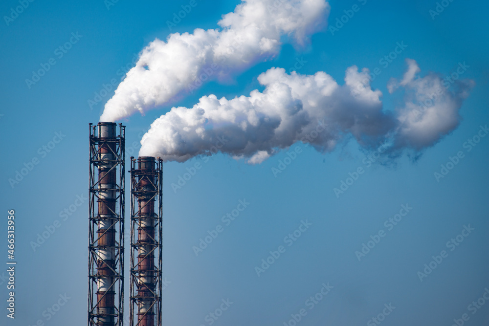 Smoke stack of coal power plant on blue sky background. Place for text