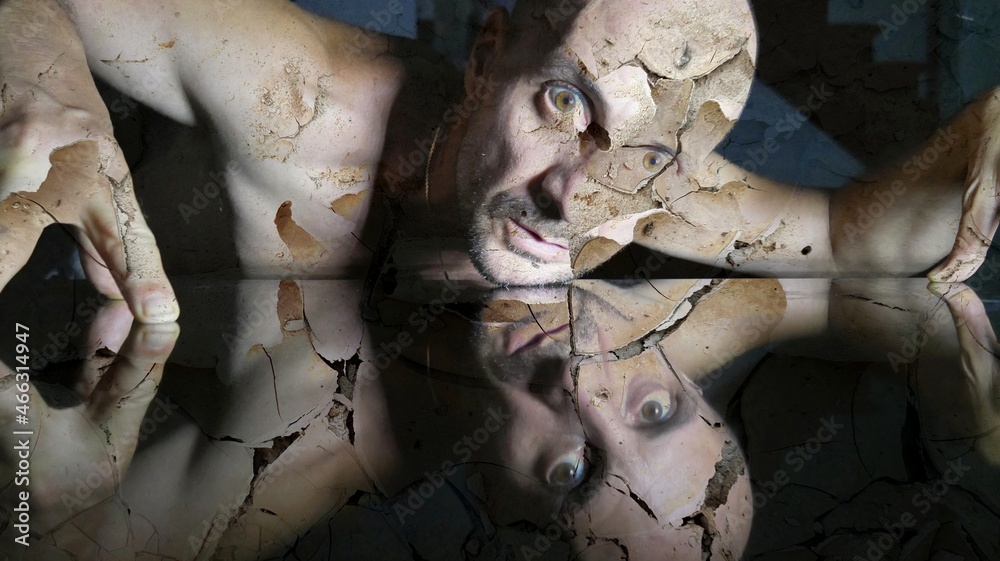 Fototapeta premium Graphic art with man with fractured body, skull fracture, distressing image of strange man with cracked skin whose body is reflected in a mirror, zombie man