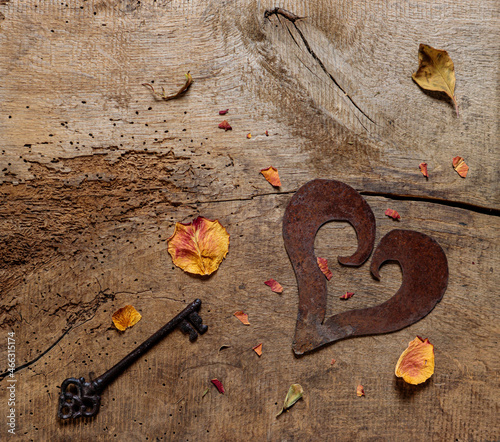 Symbol der Liebe: Schlüssel zum Herz, getrocknete Blätter einer Rose auf rustikalem Holztisch