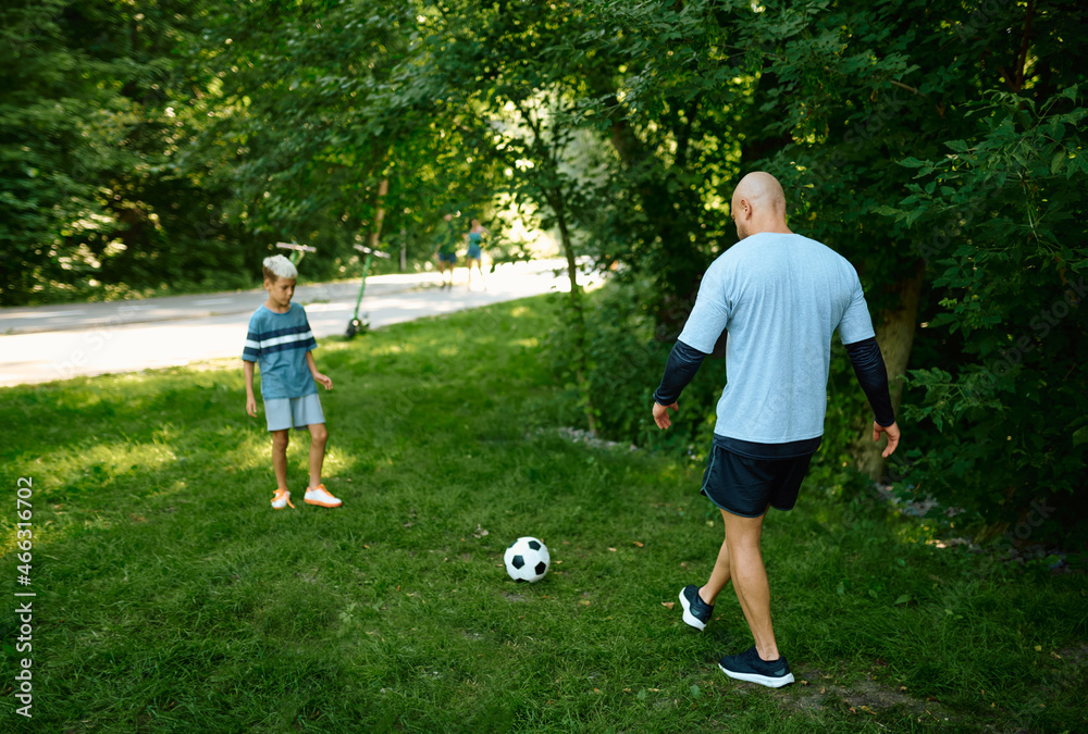 Father and son play football on the grass outdoors Father and son play football on the grass outdoors