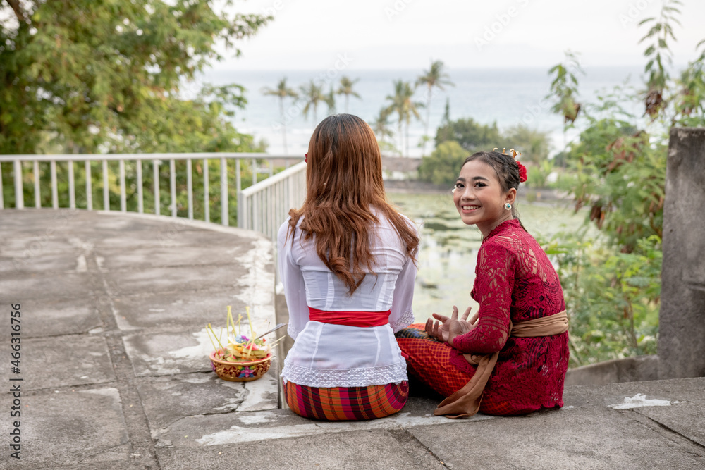 Two sitting Balinese girls overlooking palm trees. Two sitting Balinese girls overlooking palm trees.