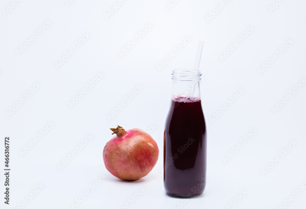 Ripe pomegranate with bottle of pomegranate juice on white background Ripe pomegranate with bottle of pomegranate juice on white background