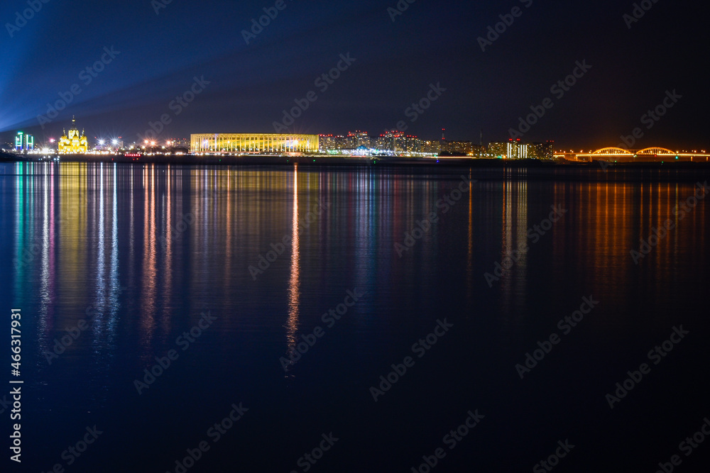 The illumination of the city is reflected in the water at night