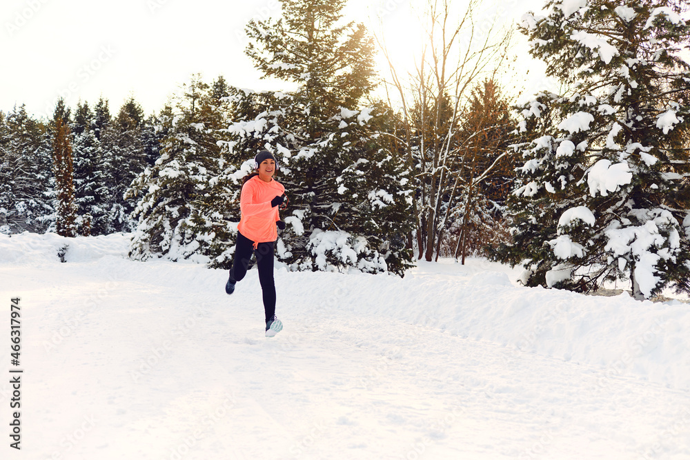 Athletic girl jogging in the snow on the nature in winter