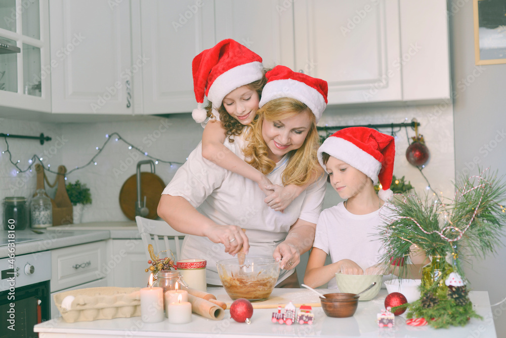 Children with mother are cooking christmas cookies. They are in the kitchen at home. Horizontal frame.
