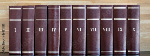 Ten book volumes in row. Roman numerals on hardback book spine. Home library bookshelf banner. photo