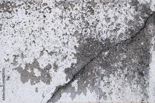 The old white concrete wall has cracks.
