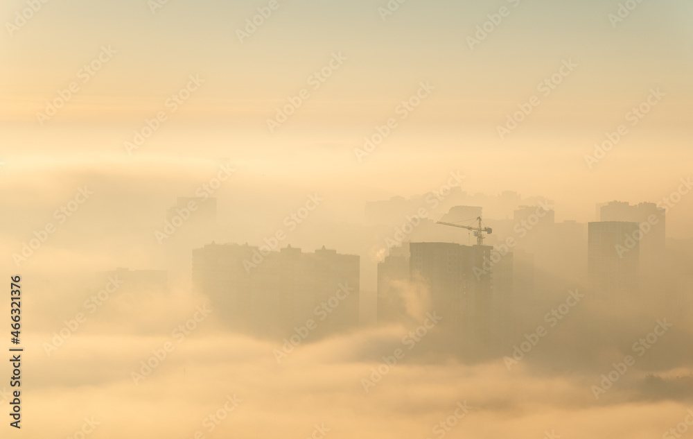 Orange sunrise over the city, construction site in fog