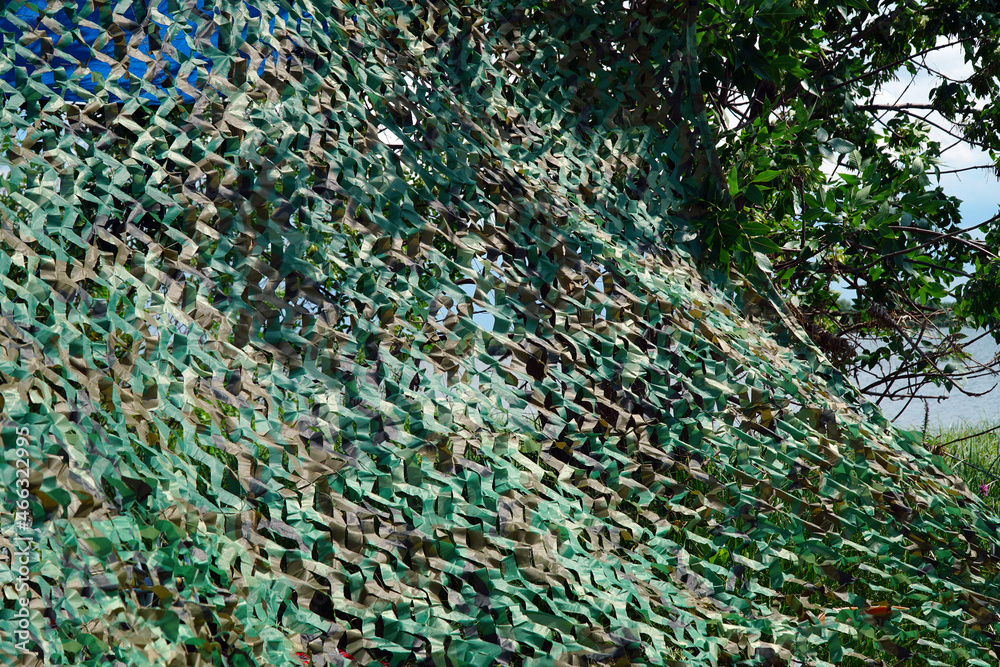 Fototapeta premium Military green camouflage net masking and covering a secret object
