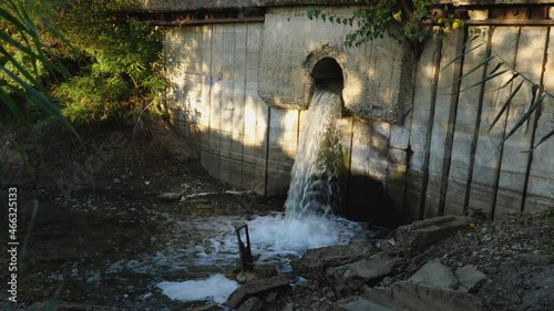 The flow of sewage water falls into the river from a pipe in a concrete wall. Environmental pollution. The concept of ecology photo