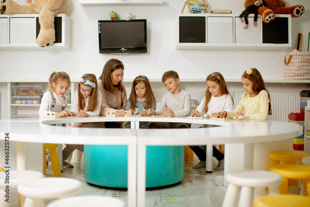 Group of cute little kids playing with preschool educational toys with kindergarden teacher Group of cute little kids playing with preschool educational toys with kindergarden teacher
