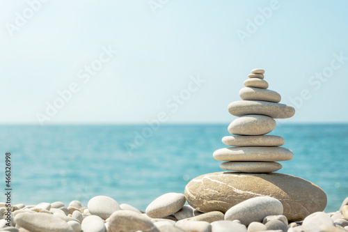 Balanced stack of pebbles on sea beach on sunny day. Natural summer harmony concept with stone pyramid on the coast.
