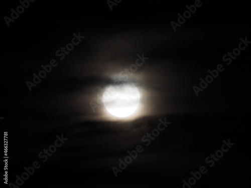 luna llena de octubre detrás de las nubes grises del cielo del pequeño pueblo de teillor, mellid, la coruña, españa, europa photo