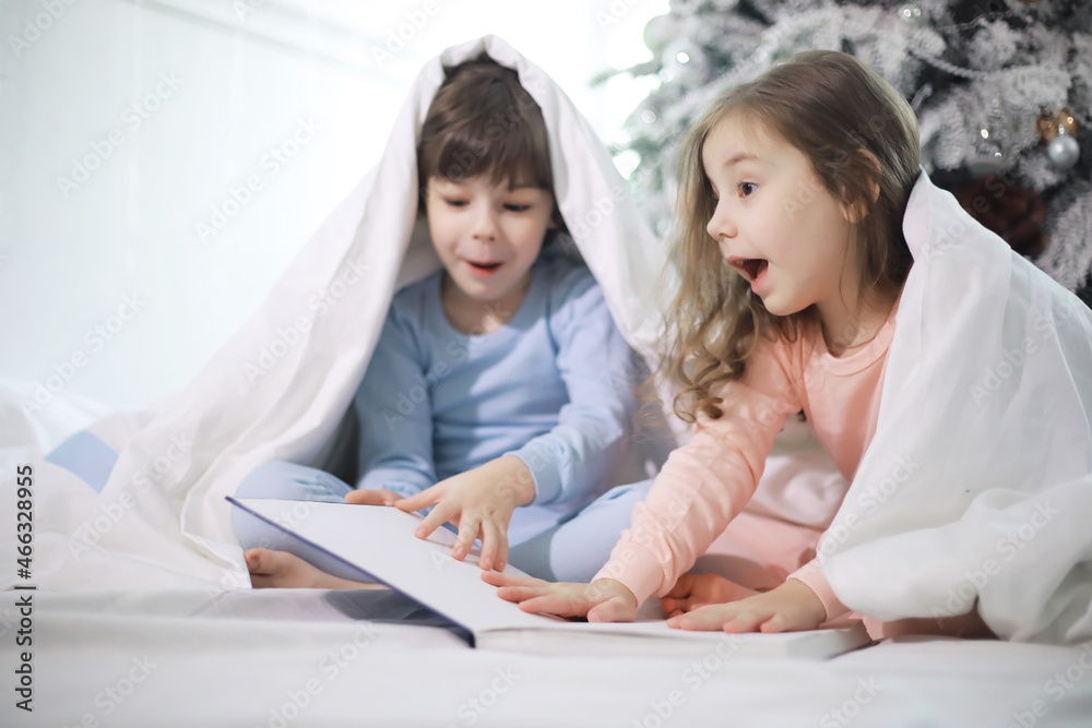 A family with children having fun on the bed under the covers during the Christmas holidays. A family with children having fun on the bed under the covers during the Christmas holidays.
