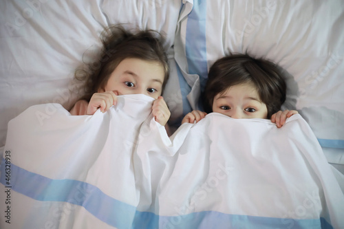 A family with children having fun on the bed under the covers during the Christmas holidays.