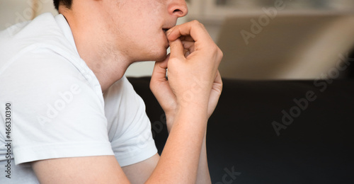 Young man feeling anxious and nervous biting nails photo