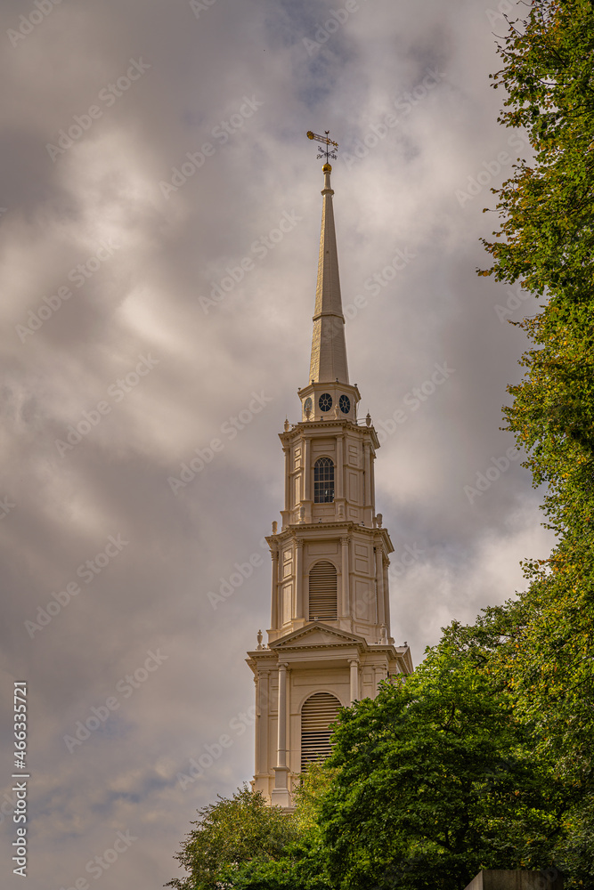 2021-10-30 AN OLD CHURCH STEEPLE IN BOSTON MASSACHUSETTS WITH CLOUDY SKYS AND GREEN TREES