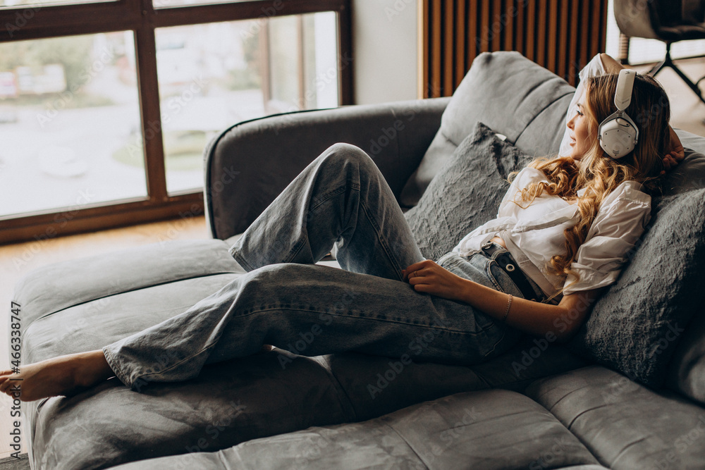 Φωτογραφία Young woman listening to music in earphones in her appartment
