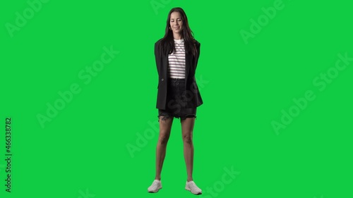 Stylish woman with hands behind back giving and offering invisible empty hand gift as surprise. Full body isolated on green screen background