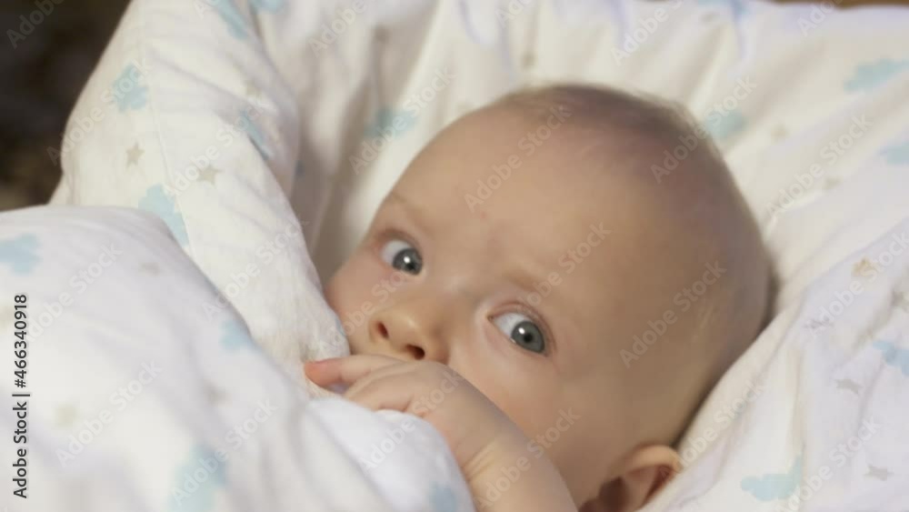 Baby wrapped in a blanket falls asleep, six month old infant face closeup. High quality 4k footage Baby wrapped in a blanket falls asleep, six month old infant face closeup. High quality 4k footage