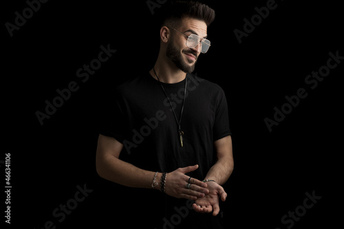 happy bearded young man with glasses looking to side and touching palms