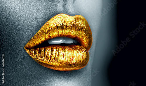 Golden lipstick closeup. Metal gold lips. Beautiful makeup. Sexy lips, bright paint on beautiful model girl's mouth, close-up. Clack and white. Metallic Lipstick closeup. Isolated on black background © Subbotina Anna