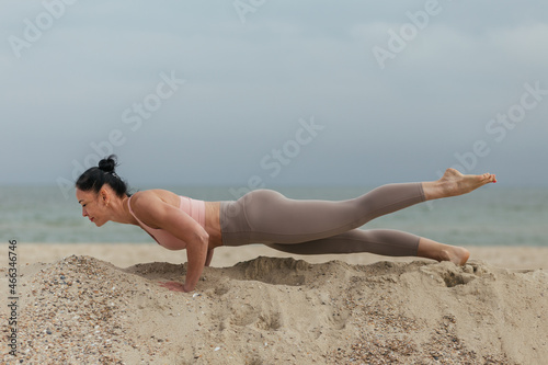 young girl doing yoga plank on the beach