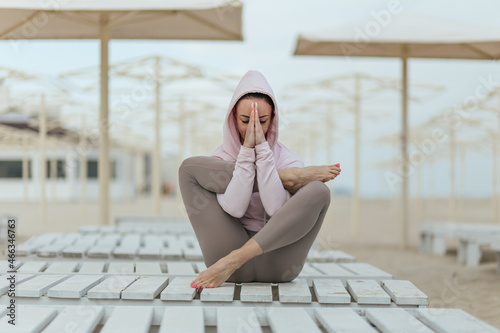 yoga postures, girl in pink hoodie sitting on a beach