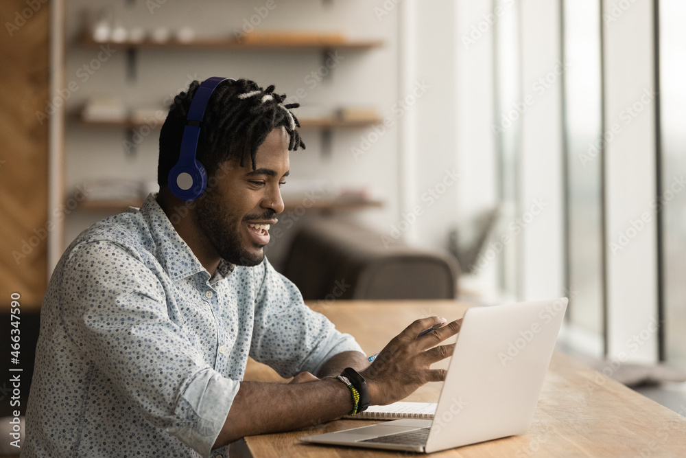 Happy young african american businessman in headphones holding video call meeting using computer application, discussing project ideas with partners or colleagues, briefing brainstorming remotely. - obrazy, fototapety, plakaty 