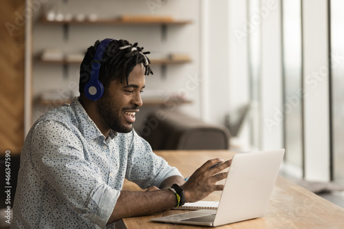Happy young african american businessman in headphones holding video call meeting using computer application, discussing project ideas with partners or colleagues, briefing brainstorming remotely.