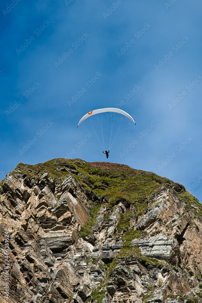 ein gleitschirmpilot überspringt überfliegt eine felskuppe, paraglider jumping over a rock summit ein gleitschirmpilot überspringt überfliegt eine felskuppe, paraglider jumping over a rock summit