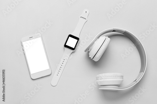 Mobile phone, smart watch and headphones on grey background