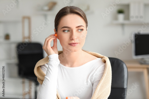 Young woman with earplugs working in office photo